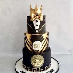 A cake fit for a king's 50th birthday. This three-tiered design in black and gold features a tuxedo on the top tier, a Versace-inspired Medusa plaque, and a golden crown.