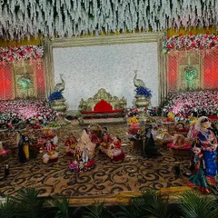 For a truly grand wedding, I filled the entire stage front with dozens of decorated gift platters and large, traditionally dressed dolls. The scale of this display, combined with the floral decor, created a tumba luxury feel.