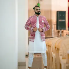 I love seeing my clients own their look. This custom-made open Jodhpuri jacket features bold red and white embroidery, layered over a simple white kurta set for a sharp, celebratory feel.