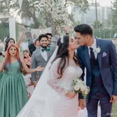 A beautiful kiss seals the vows at a Christian wedding, with the wedding party cheering in the background. I love capturing the energy and support of friends and family on the big day.