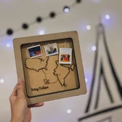 A perfect farewell gift for a friend moving from India to the USA. This custom map frame features laser-cut outlines of both countries, mini polaroids of shared memories, and a fun "Bring Dollars" message.
