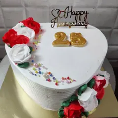 A heart-shaped cake for a 25th anniversary. It's decorated with red and white buttercream roses and colorful sprinkles for a festive look.