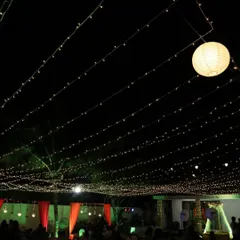 Even simple lighting can be impactful. Here, a dense canopy of fairy lights creates a starry night effect over an outdoor seating area, with paper lanterns adding a soft, ambient glow for a relaxed corporate mixer.
