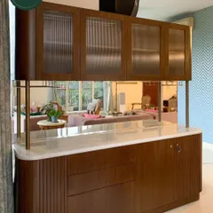 This custom-designed bar and crockery unit showcases our expertise in creating functional art. The rich wood finish, curved corners, and fluted glass doors provide a sophisticated storage solution that seamlessly divides and enhances the living space.