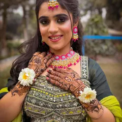 A happy bride-to-be showing off her complete Mehendi look. The green and pink color combination is a classic choice.