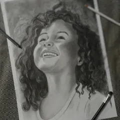 A charcoal painting that beautifully captures the pure joy on a little girl's face. This piece is a great example of using black and white to convey strong emotion.