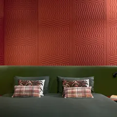 This 'Wave Flanelle' wallcovering is crafted from pure wool, forming a tactile, three-dimensional surface. The quilted undulations not only enhance the visual appeal but also provide acoustic benefits, making the bedroom both beautiful and serene.