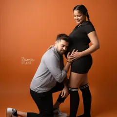 He listens to the baby bump while she stands strong and smiling. This is a sweet and creative shot from their unique fitness themed pregnancy photoshoot.