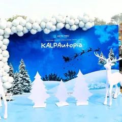 A wide view of the 'KALPAutopia' corporate winter festival setup, showcasing a large custom-printed backdrop with the company's branding. We flanked the scene with life-sized reindeer props and decorative trees to create an immersive experience.