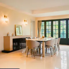 The dining area in the Guwahati residence features elegant crystal wall sconces that flank a console table. This lighting choice adds a touch of legacy and architectural character to the space.
