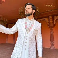 A close-up of our custom white sherwani, showing the intricate threadwork and the elegant pearl and pink stone necklace it's paired with.