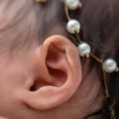 The perfect little swirl of a newborn's ear, adorned with a delicate pearl headband. It’s these tiny features that make them so unique.
