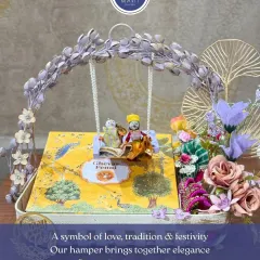 This Teej hamper is a symbol of love, tradition, and festivity. The centerpiece is a ghewar box, surrounded by other essentials, all presented in a beautiful basket with a decorative swing.