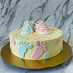 Boy or Girl? This gender reveal cake features tiny, hand-sculpted fondant baby shoes in pink and blue. The little footprints and pastel polka dots add to the adorable design.