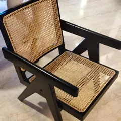 A close-up of the iconic Pierre Jeanneret-inspired lounge chair, showing the flawless black finish on solid teak and the intricate hand-woven cane seat and back. This design is a cornerstone of my mid-century modern collection.