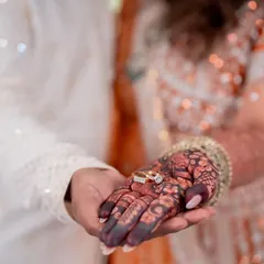A beautiful moment captured, with the engagement rings resting on the richly stained henna, symbolizing the promise of a lifetime together.