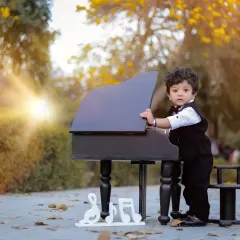 A different angle of our little pianist, showing his curiosity as he stands by the miniature piano. This pose adds variety to the gallery from a single session.