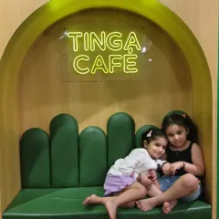 Two sisters cuddle up in the green booth at Tinga Cafe after a day of play.