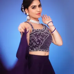A dynamic portrait using a solid blue backdrop to create a high-fashion look. The movement in the dupatta adds energy to this modern ethnic wear shot.