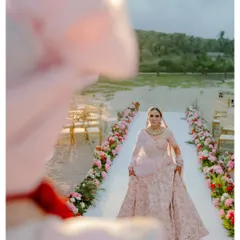 The bride's grand entrance. Walking down an aisle lined with flowers on the sand, her expression is a beautiful mix of excitement and grace. The beach setting makes this classic moment feel fresh and magical.