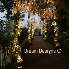 An ethereal walkway for an evening event. The path is lined with illuminated floral arrangements and features a ceiling of hanging chandeliers, creating a breathtakingly romantic and luxurious experience.