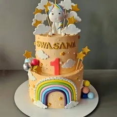 A peachy unicorn cake for Swasana's first birthday. This vanilla cake with salted caramel features a cute unicorn, a pastel rainbow, and fluffy clouds.