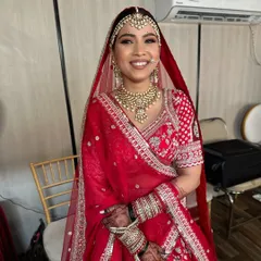 The complete traditional bridal look. This bride is radiant in her red lehenga, with perfectly draped dupatta, intricate jewelry, and makeup that highlights her joyful smile.