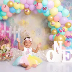 Pure happiness! A joyful shot from a first birthday session, where the birthday girl waves her hands in excitement. The colorful unicorn-themed setup makes the moment even more magical.