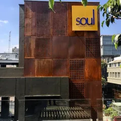 The completed commercial building in Koramangala, showing the realized corten steel facade with custom perforations and prominent signage.
