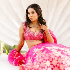 Shree seated against a shell-inspired backdrop, showing off the beautiful flare of her pink Anita Dongre lehenga. A perfect Mehendi look.