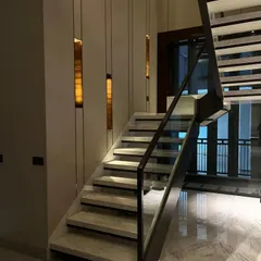This view of the geometric staircase highlights the integrated wall lighting. Vertical slits of warm light create a rhythm along the wall, guiding the way and adding to the architectural drama.