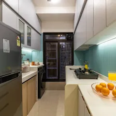 This galley kitchen feels spacious thanks to light-colored overhead cabinets, under-cabinet lighting, and a continuous countertop that wraps around the corner.