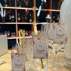 Elegant custom tags for a wedding, featuring the couple's initials and their hashtag, '#JasWeMetEachOther', clipped to the glassware.