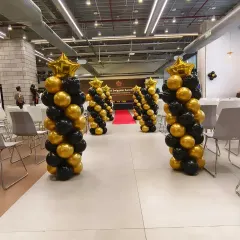 Here is another view of the balloon pillar arrangement for the Swiggy corporate event. The spiral design in the company's brand colors adds a touch of sophistication and visual interest to the large event hall.
