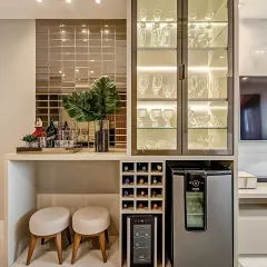 Even a small corner can become a stylish home bar. This compact unit features a glass display cabinet, a wine rack, and space for a mini-fridge, all tied together with a mirrored tile backsplash.