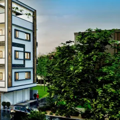 A closer look at the ultra-chic facade, highlighting the contrast between the smooth white surfaces and dark window details. The surrounding greenery is intentionally integrated to soften the modern architectural lines.