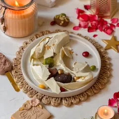 The aftermath of the smash, revealing the delicious assortment of chocolates, pralines, and dates hidden inside the white chocolate moon. It's a treat that's as fun to eat as it is to break.