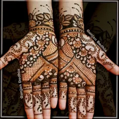 A full-coverage Indian mehendi design. The pattern combines floral elements, peacock motifs, and leafy vines on the fingers for a dense and beautiful look.