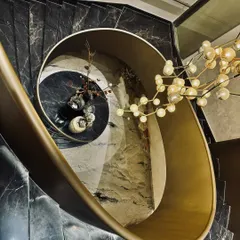 A staircase can be more than just a connection between floors; it can be the heart of a home. We designed this sculptural, spiral staircase with black marble treads and a flowing brass balustrade, turning a functional element into a central piece of art that is dramatic from every angle.