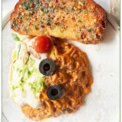 Spreading happiness, one delicious meal at a time. This plate features a duo of pastas, one with a creamy pesto sauce and the other with a rich tomato sauce, served with garlic bread.