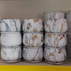 A stack of modern, stylish ceramic pots with a marble finish and matching saucers. These are perfect for elevating the look of your indoor plants.