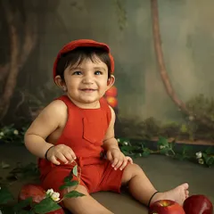 A sweet, smiling portrait of the baby amidst the apples. The painterly backdrop and thoughtful styling create a whimsical, storybook feel.