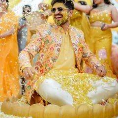 A fantastic shot of the groom being showered with flower petals by his friends and family during the Haldi ceremony.