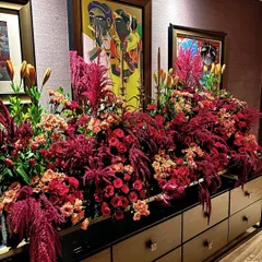 A stunning floral arrangement designed for a festive celebration. We combined deep red roses, dramatic amaranthus, and orange lilies against a backdrop of contemporary art to create a look of modern opulence.