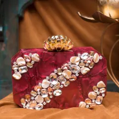 A bold and beautiful choice, this ruby-red acrylic clutch is lavishly decorated with a cascade of clear and champagne-colored rhinestones. The golden lotus clasp adds a touch of regal elegance.