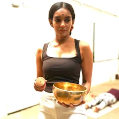 Holding a singing bowl, a key instrument in my sound healing sessions. Each bowl has a unique frequency that helps to balance the body's energy centers, promoting a state of deep calm and mental clarity.