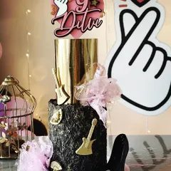 I made this Blackpink-themed cake for my daughter's birthday. It features a dramatic black textured tier and a metallic gold top tier, accented with guitars, a high heel, and the K-pop heart sign.
