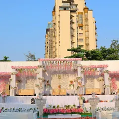 A daytime view of an outdoor wedding stage I decorated. The pink and white floral theme creates a classic and elegant look against the urban backdrop of Navi Mumbai.