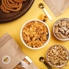 A bright and cheerful spread of my most popular savory snacks. This flat lay shows the vibrant colors of the corn mixture, the golden brown of the hing jeera peanuts, and the perfect spirals of my garlic murukku.