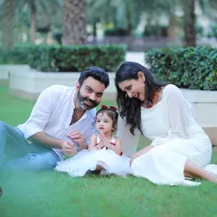 A family enjoying a beautiful day outdoors, sitting together on the grass. Our outdoor sessions are perfect for capturing natural interactions and candid smiles.